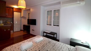 A bedroom with a bed, a bedside table, a TV, and a window. - Apartamentos Good Stay Atocha (Madrid)