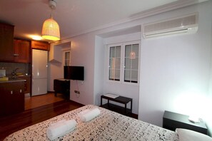 A bedroom with a bed, a bedside table, a TV, and a window. - Apartamentos Good Stay Atocha (Madrid)