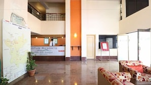 A hotel lobby with a reception desk, a map, seating area, and a staircase. - Vits Kamats Resort (Silvassa)