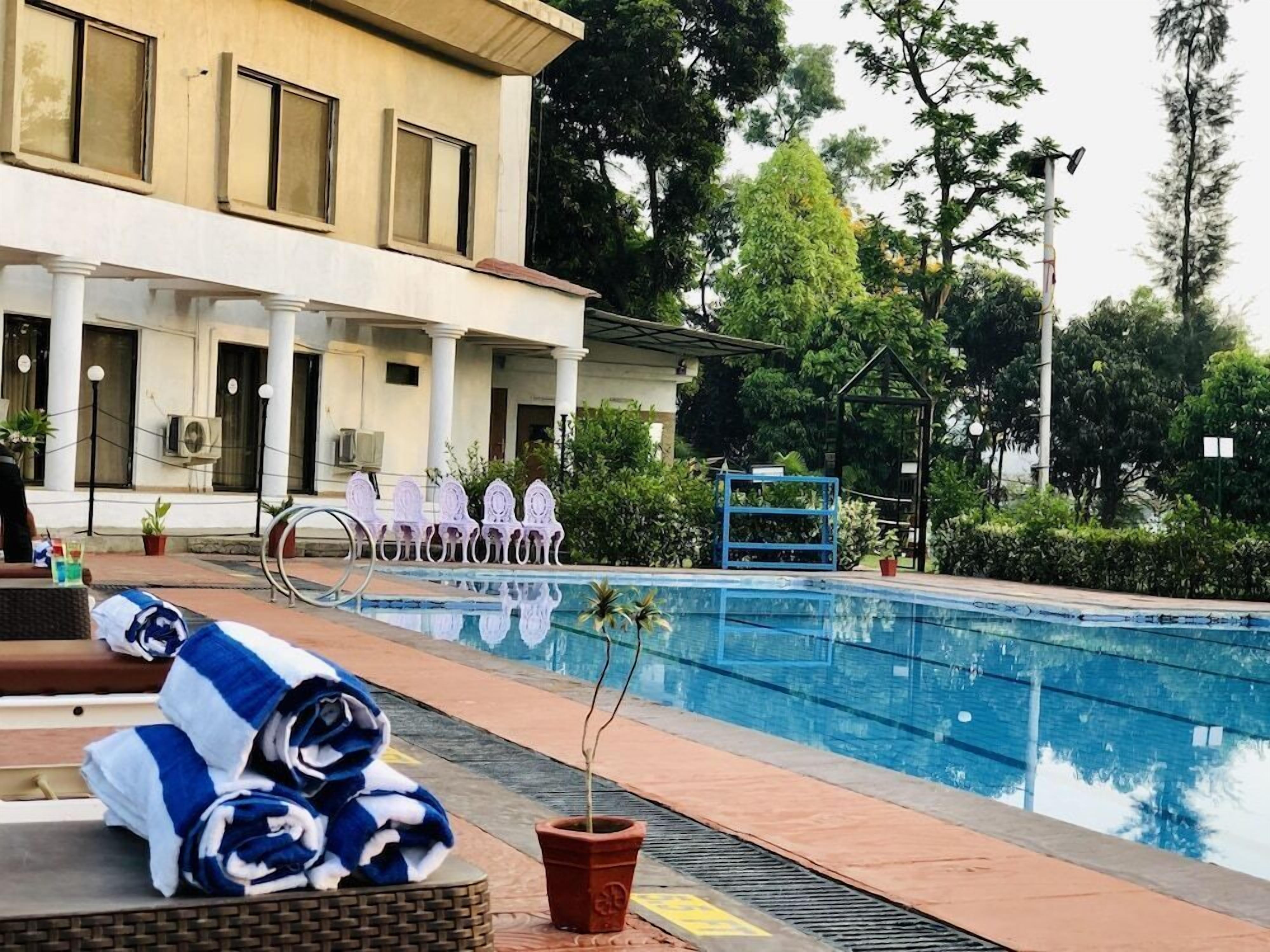 A swimming pool with lounge chairs and a building with columns.
