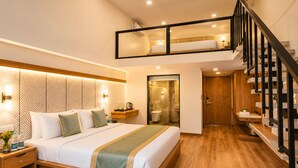 A modern hotel room with a large bed, a wooden floor, a balcony, and a staircase. - Vits Kamats Resort (Silvassa)