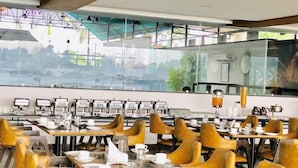 A dining area with tables set for breakfast, chairs, and a view of the outside. - Vits Kamats Resort (Silvassa)