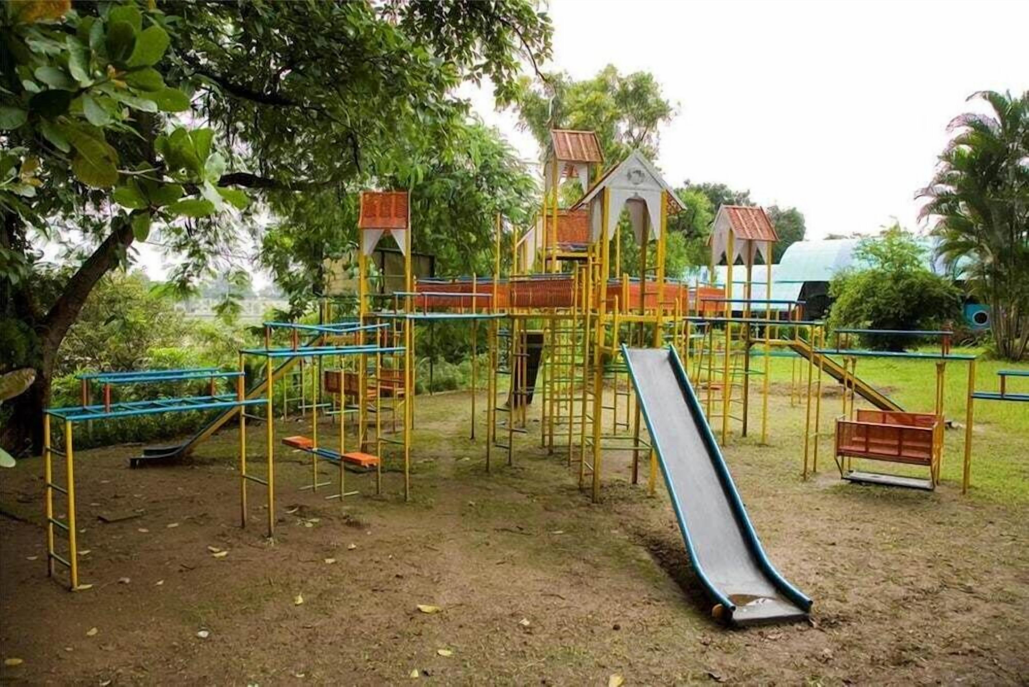 A playground with various play structures including a slide, climbing frames, and a small building.