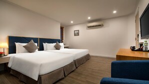 A hotel room with a double bed, a desk with a chair, an air conditioning unit, and a television. - Bonsella Cozy Hotel (Hanoi)