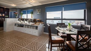 A modern kitchen with a marble countertop, a dining area with a table and chairs, and a large window with a city view. - Bonsella Cozy Hotel (Hanoi)
