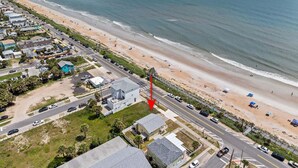 Luftaufnahme einer Küstenlandschaft mit Strand, einer Straße und Gebäuden.