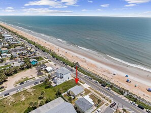 An aerial view of a coastal area with a beach, a road, and buildings. - Ocean Views, Beach Across Street & Pet-Friendly | Sunrise Cottage (Flagler Beach)