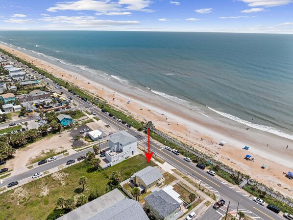 An aerial view of a coastal area with a beach, a road, and buildings.