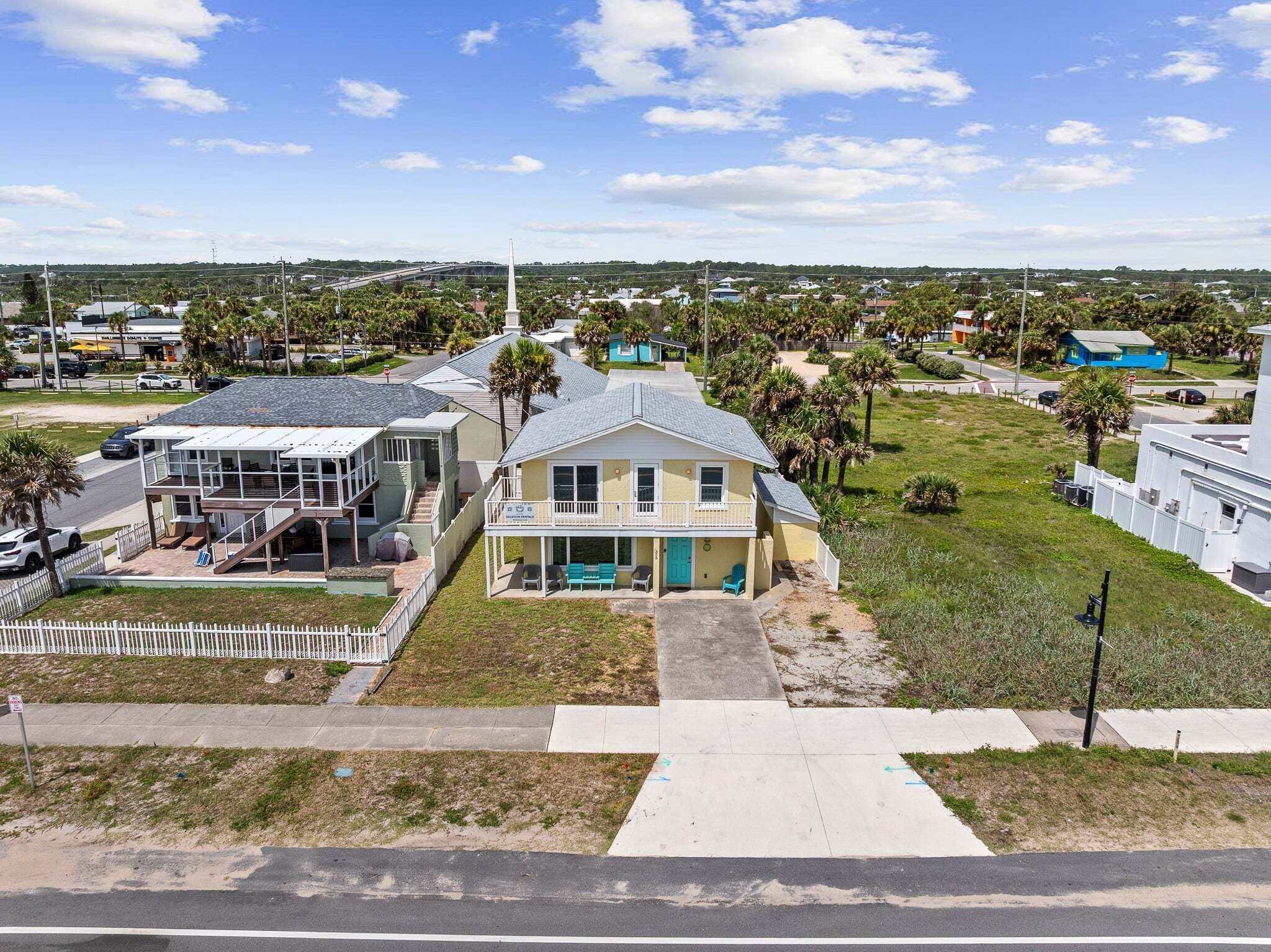 Una zona residencial costera con casas, cerca blanca y cielo despejado.