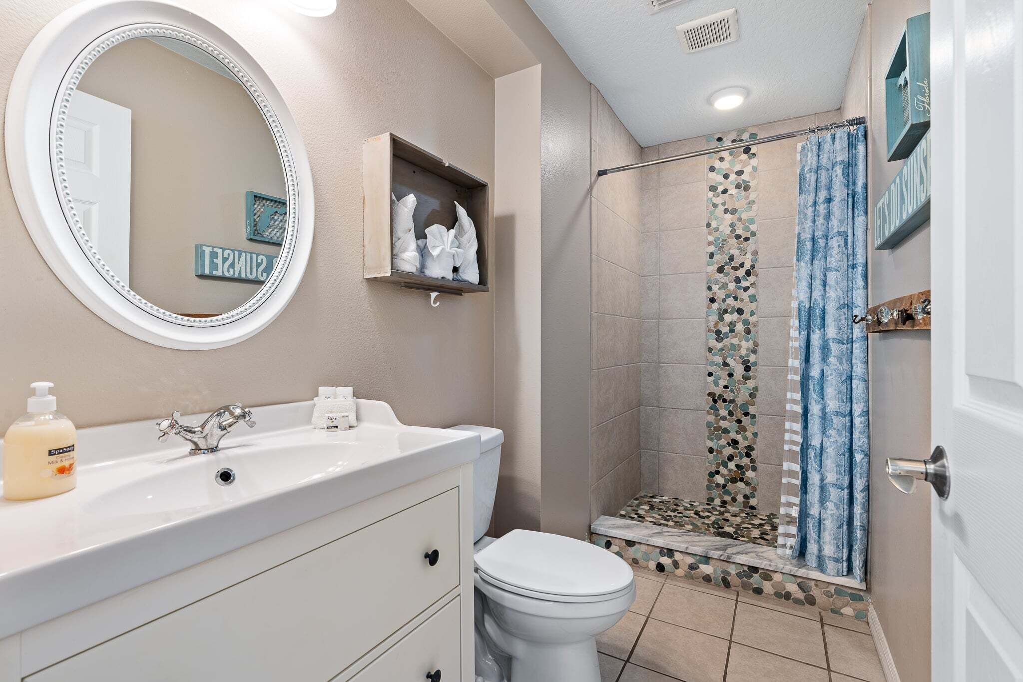 Un baño con lavabo, inodoro, espejo, ducha y toallero.