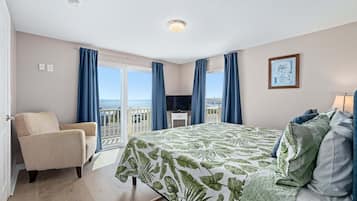 A hotel room with a bed, a chair, a TV, and a balcony with a view.