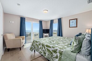 A hotel room with a bed, a chair, a TV, and a balcony with a view.