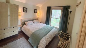 Ein Schlafzimmer mit Bett, Kleiderschrank und einem Vorhangfenster.