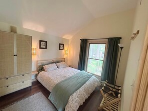 Ein Schlafzimmer mit Bett, Kleiderschrank und einem Vorhangfenster.