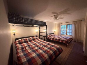 Ein Zimmer mit zwei Betten, einem Deckenventilator und einem Vorhangfenster.