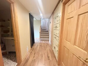 Ein Flur mit Holzdielen, einer Treppe und einer Holztür mit mehreren Schubladen.