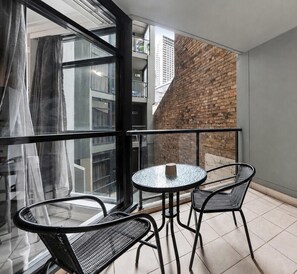 Ein Balkon mit Glastür, einem runden Tisch und zwei Stühlen.