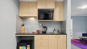 A compact kitchen with a microwave, sink, and storage cabinets.