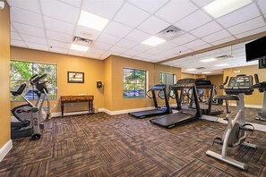 A gym with exercise equipment, a bench, and large windows. - Wizard-Themed Condo Near Universal (Orlando)