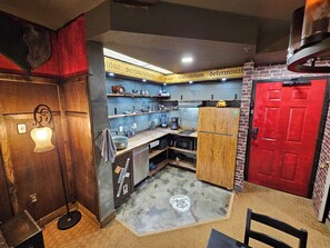 A compact kitchen with a red door, wooden cabinets, and a countertop with various appliances. - Wizard-Themed Condo Near Universal (Orlando)