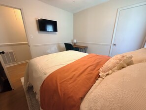Een hotelkamer met een bed, bureau, stoel, televisie en een deur.