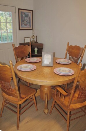 Een ronde houten eettafel met zes stoelen, een bord met een welkomstboodschap en een vaas op een bijzettafeltje.
