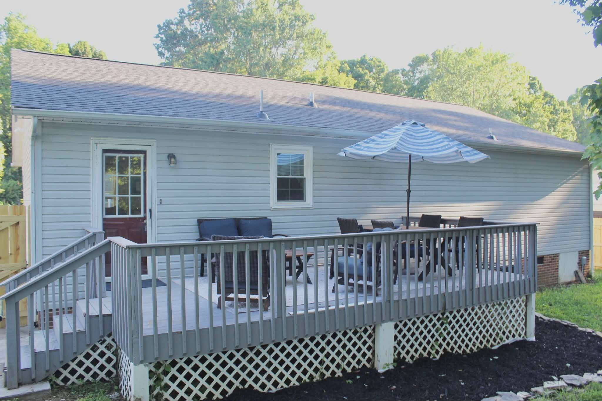 A house with a deck, a covered patio, and a fenced area.