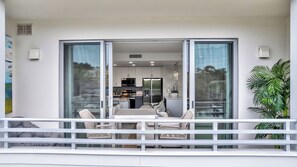 A modern interior with a dining area, kitchen, and sliding glass doors leading to a balcony. - Luxury Bayfront Designer Retreat • Paddleboard • Stunning Sarasota Sunsets (Sarasota)