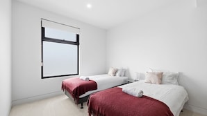 A hotel room with two beds, a large window, and a carpeted floor. - Domi Rentals - The Cheltenham Southland House (Cheltenham)