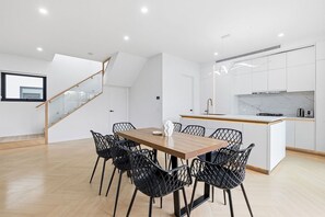 A modern kitchen with white cabinets, a wooden island, and a built-in stove. - Domi Rentals - The Cheltenham Southland House (Cheltenham)