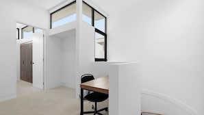 Une pièce comprenant un bureau, une chaise et une fenêtre. Une porte donne accès à une autre pièce.