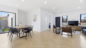 Un intérieur moderne comprenant un coin repas, des sièges, un téléviseur et une grande fenêtre.
