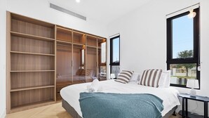 Une chambre à coucher comprenant un lit, une grande armoire, une fenêtre et une table de chevet.