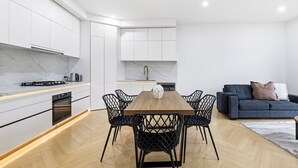 Eine moderne Küche mit weißen Schränken, einem Holztisch und schwarzen Stühlen.