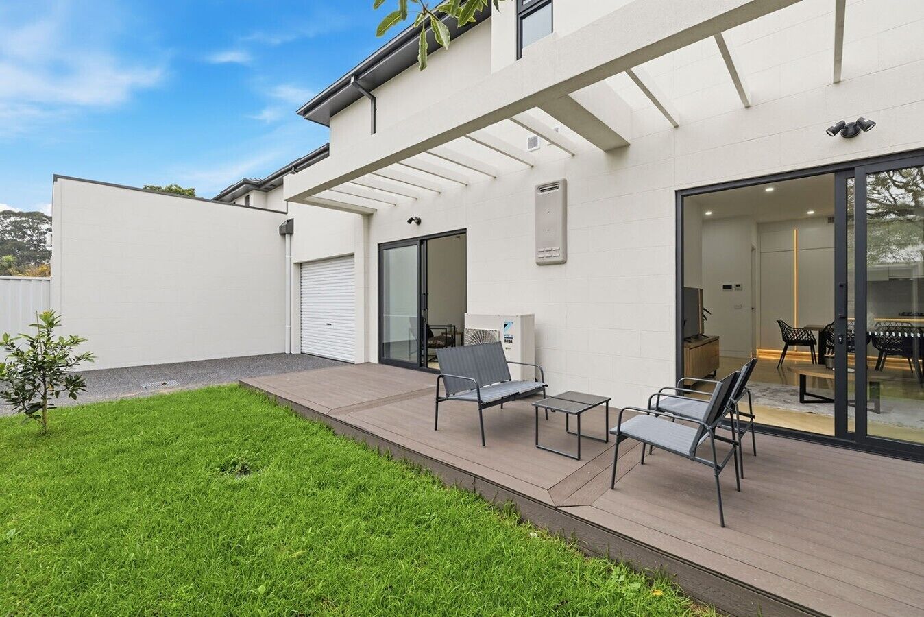 A modern house with a covered patio, a garage, and a dining area with outdoor furniture.