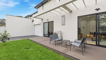 A modern house with a covered patio, a garage, and a dining area with outdoor furniture.