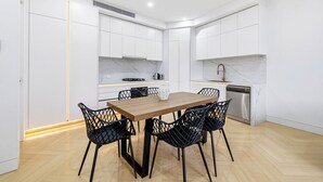 Eine moderne Küche mit weißen Schränken, einem Holztisch und schwarzen Stühlen.