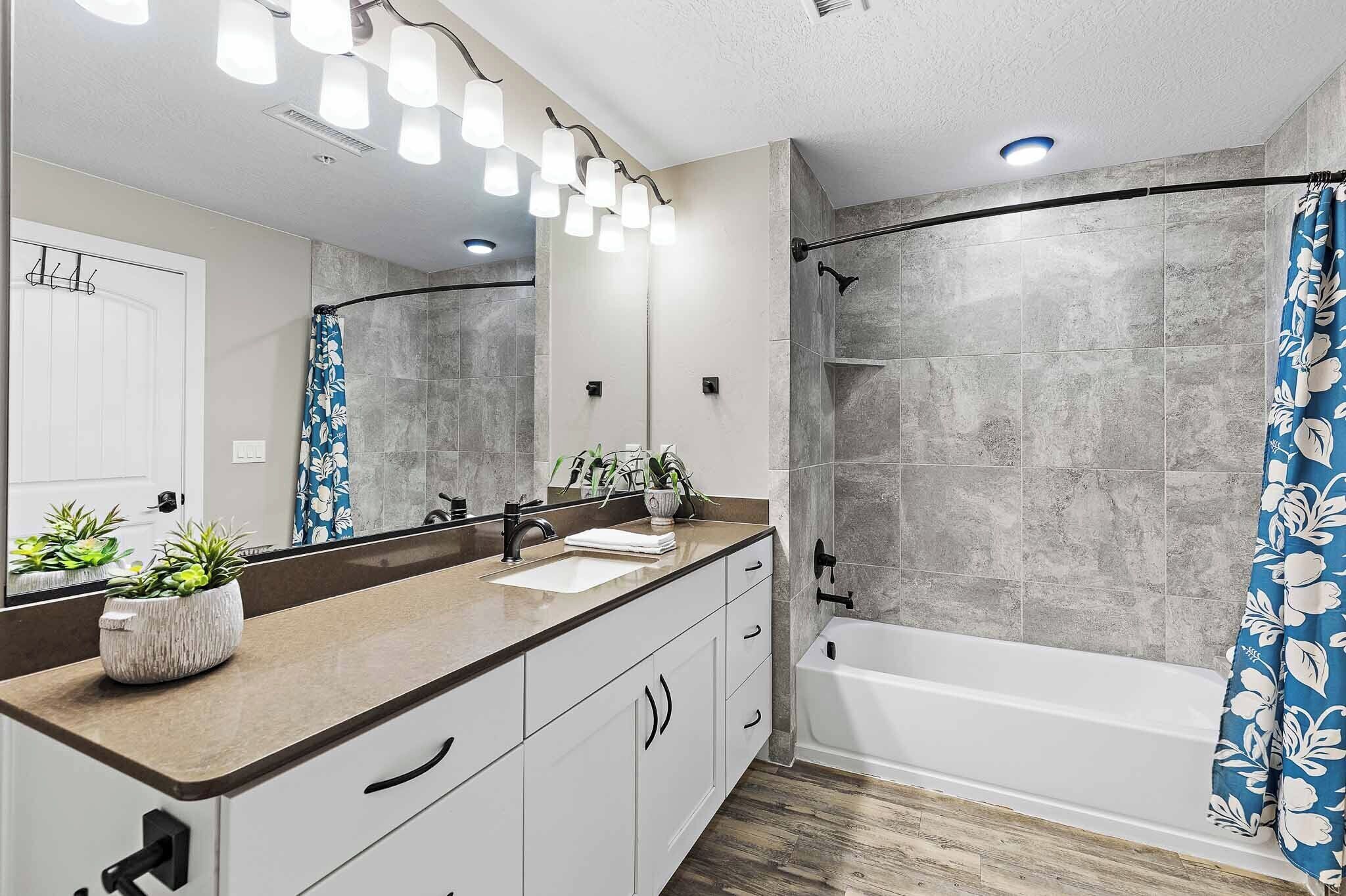 Een moderne badkamer met een grote spiegel, een badkuip, een douche en een wastafelmeubel met een wastafel.