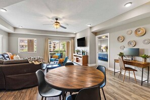 Ein modernes Wohnzimmer mit Sofa, Esstisch, Stühlen und Deckenventilator.