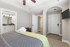 Ein Hotelzimmer mit Bett, Badezimmer mit Spiegel, Dusche und einem an der Wand befestigten Fernseher.