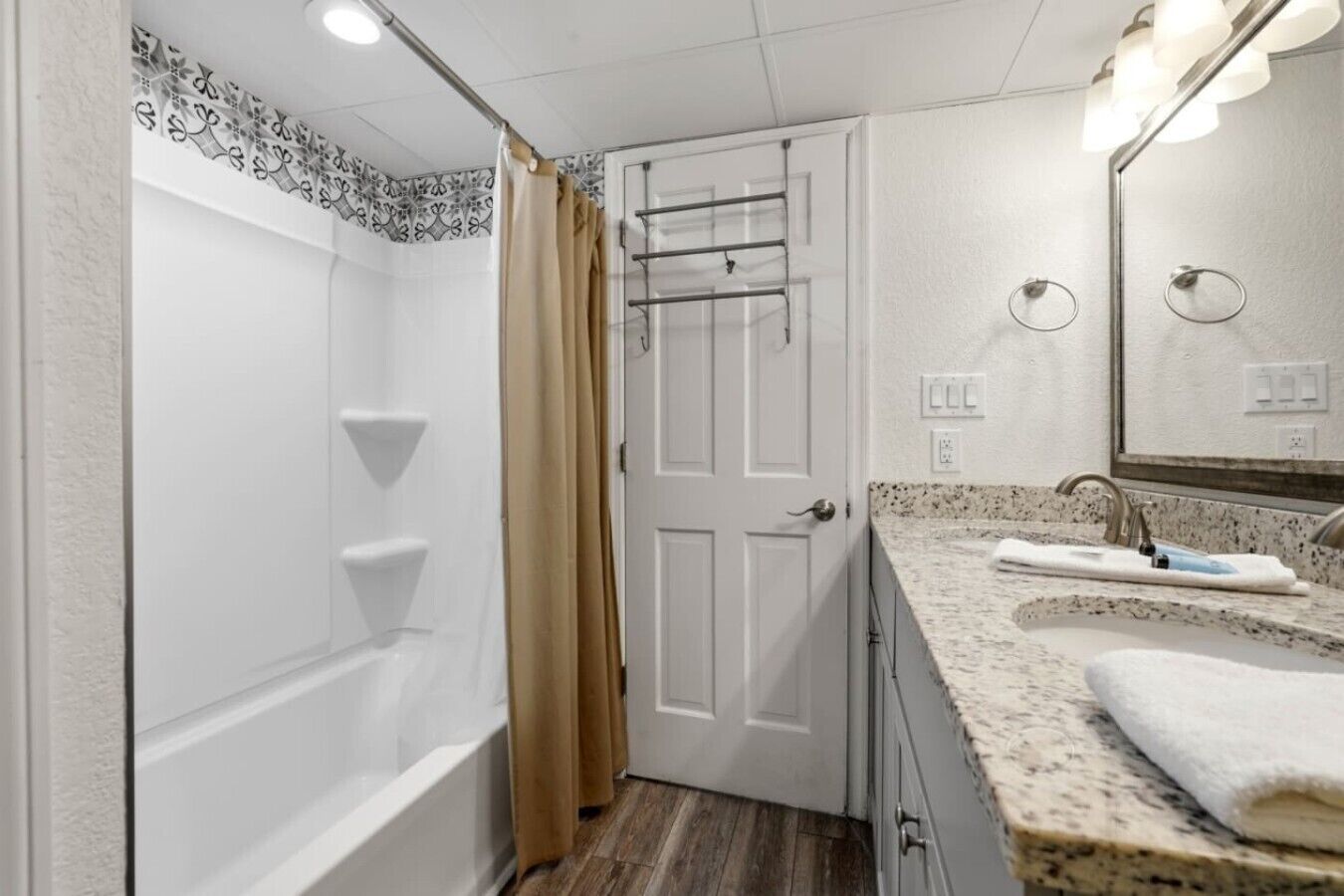 A bathroom with a bathtub, a shower curtain, a towel rack, a sink with a mirror, and a towel.