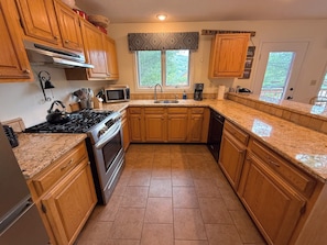 A kitchen with wooden cabinets, a stainless steel stove, a microwave, and a dishwasher. - W38: Spacious 5BR Slope-View Retreat | Ping Pong, Fireplace & Bretton Woods Adventure (Bretton Woods)