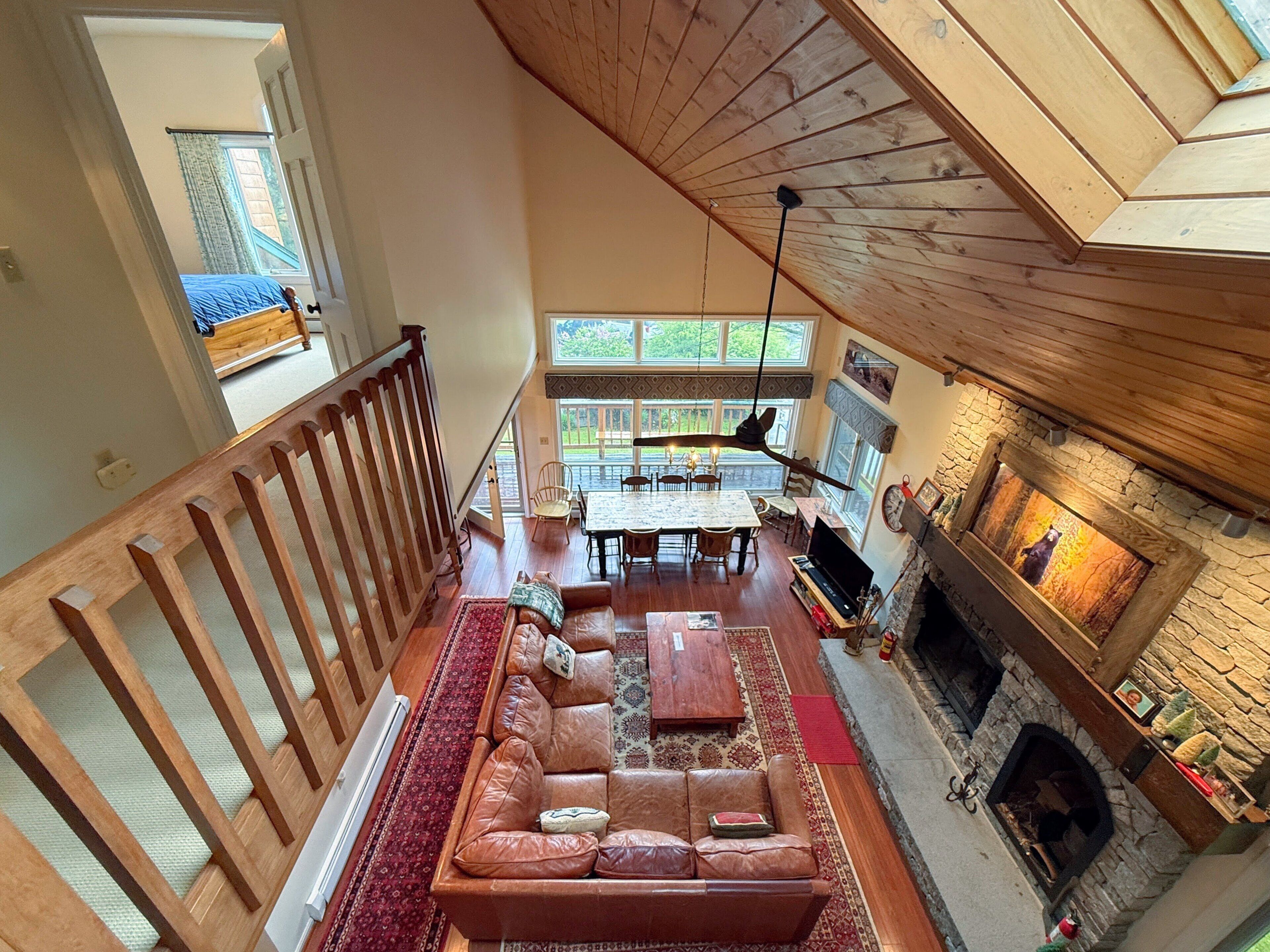 A spacious loft-style living area with a high ceiling, a fireplace, a dining table, and a cozy seating arrangement.