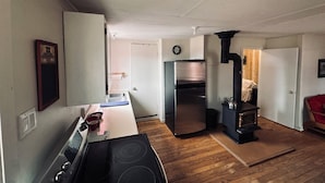 Una cocina funcional con estufa, refrigerador y estufa de leña.