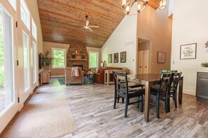 A spacious dining area with a wooden ceiling, a fireplace, and a view of the outdoors. - Scout's Retreat (Green Township)