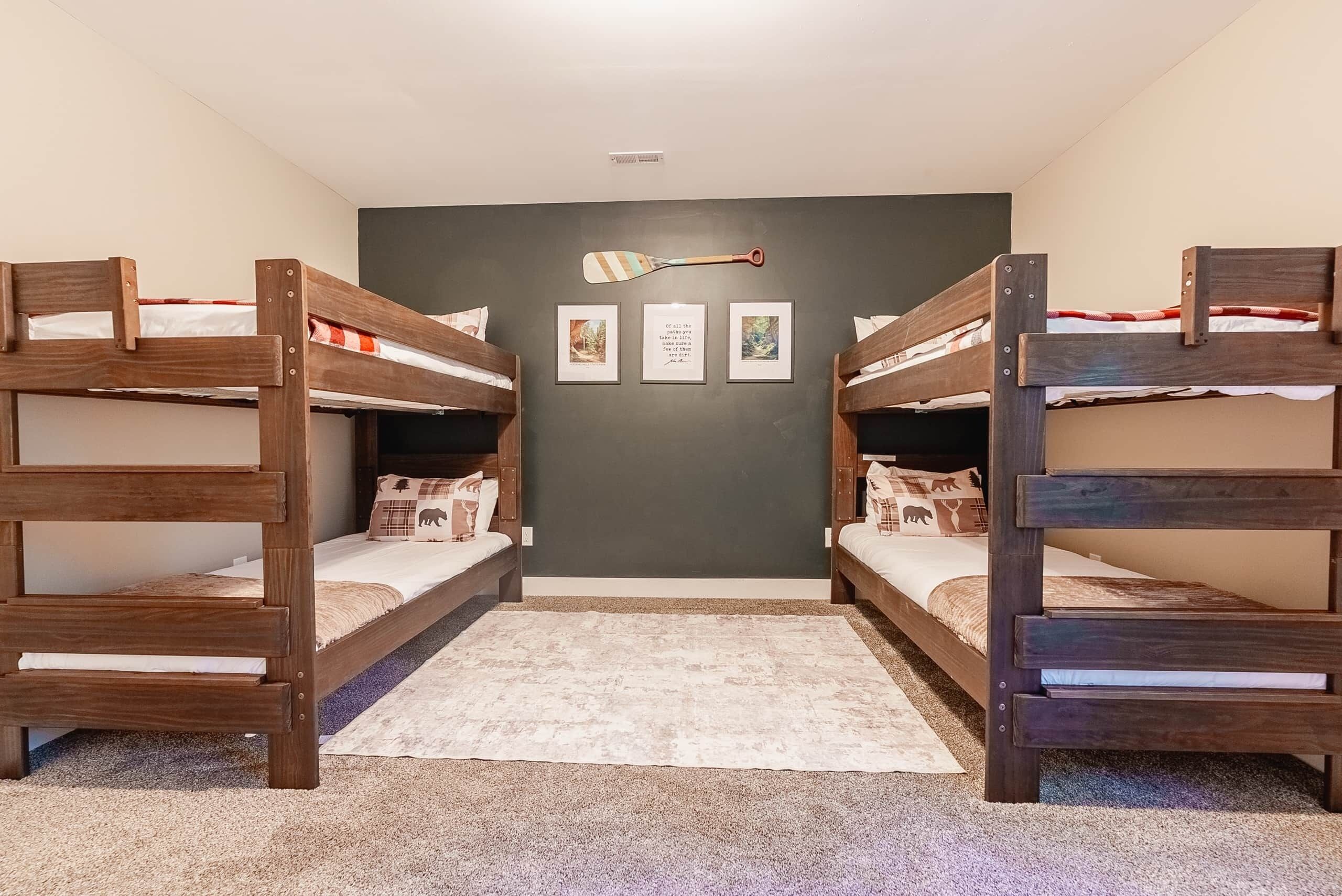 Una habitación con literas, un tapete pequeño y tres cuadros en la pared.