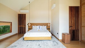 Ein Schlafzimmer mit einem Bett, einem Holz-Kopfteil, Nachttischlampen, einem kleinen Nachttisch, einer Wand-Klimaanlage und einem Fenster mit Blick auf Grünflächen.