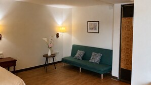 Una stanza con un divano verde, un tavolino con un vaso di fiori, una lampada e un quadro appeso al muro.