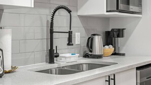 A kitchen with a modern faucet, a stainless steel sink, and a kettle on the counter. - Latobir Modern,stylish 2BR Suite Private Entrance (Calgary)