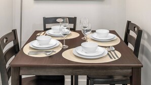 A dining table set with white plates, bowls, and cutlery, accompanied by two wine glasses. - Latobir Modern,stylish 2BR Suite Private Entrance (Calgary)